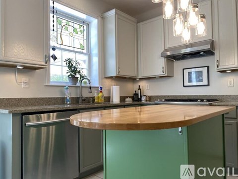 A kitchen with a green island and stainless steel appliances.