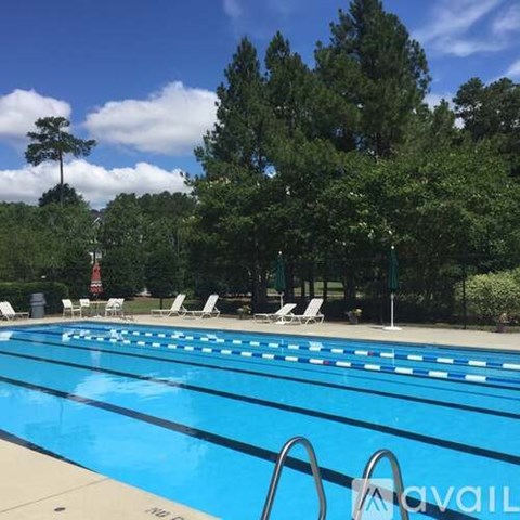 A swimming pool surrounded by trees and chairs.
