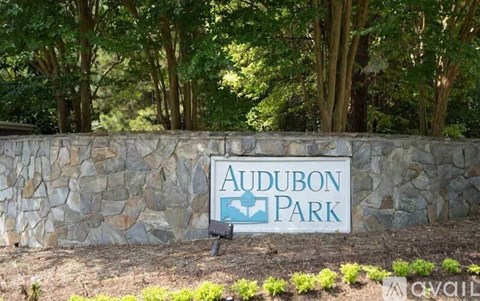 A sign that says Audubon Park in front of a stone wall.