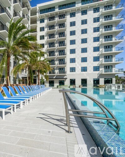 A pool area with a slide in front of a white building with balconies.