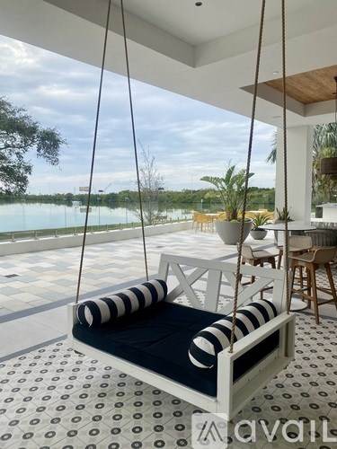 A white and black striped swing chair is suspended from the ceiling by ropes.