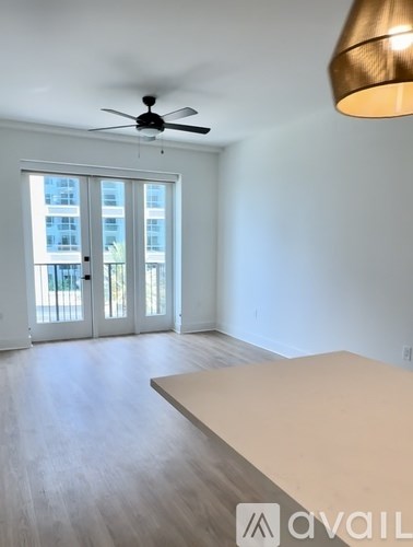 A room with a ceiling fan and a large window with a view of a building outside.