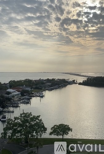 A view of a harbor with boats docked and buildings along the shore under a cloudy sky.