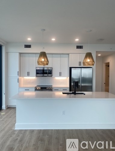A modern kitchen with a white countertop and stainless steel appliances.