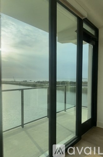 A glass door with a view of a body of water and a cloudy sky.