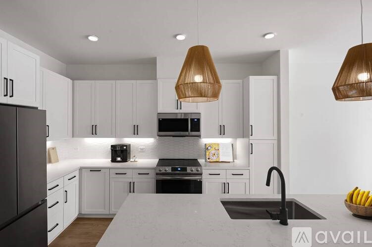 A modern kitchen with white cabinets and a dark refrigerator.