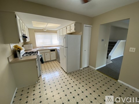 A kitchen with a tile floor and a refrigerator.