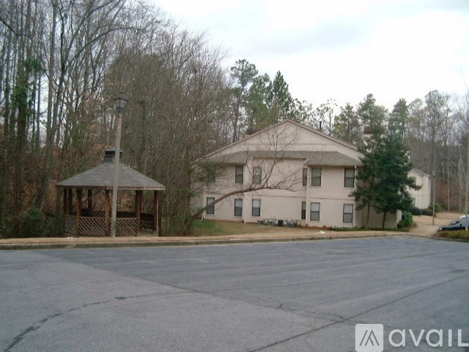 A gazebo is in front of a building with a parking lot in the foreground.