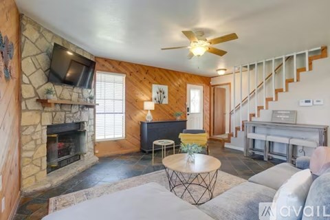 A living room with a stone fireplace and a television above it.