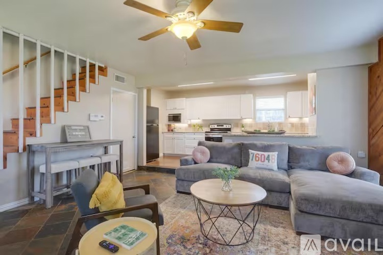A living room with a grey couch, a coffee table, and a ceiling fan.