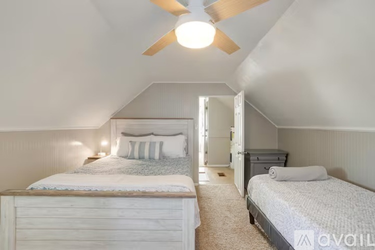 A bedroom with two beds and a ceiling fan.