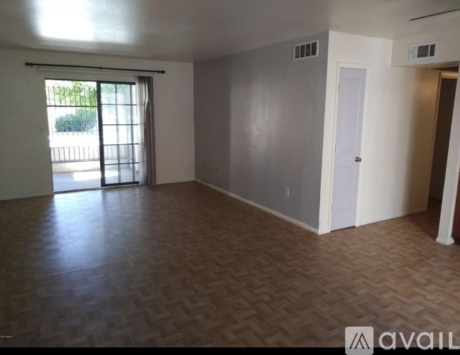 A room with a wooden floor and a sliding glass door leading outside.