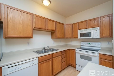 A kitchen with wooden cabinets and white appliances.