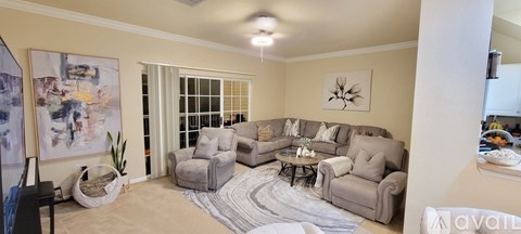 A living room with a grey sofa set and a painting on the wall.