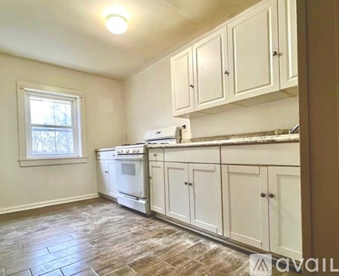 A kitchen with white cabinets and a window.