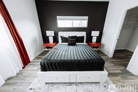 A bedroom with a black bed and red curtains.