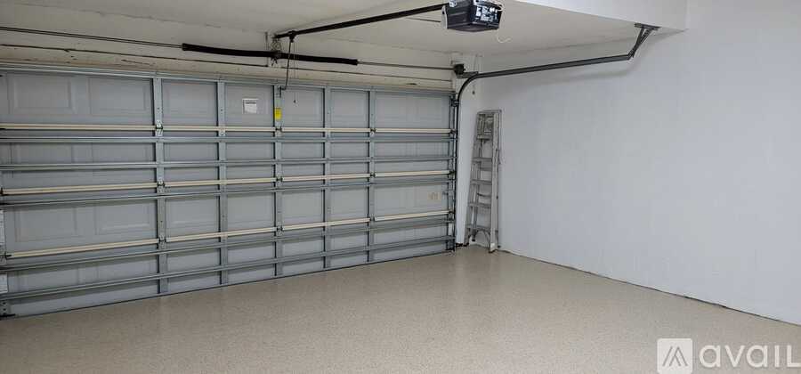 A spacious garage with a closed shutter door and a ladder.