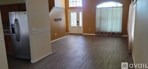 A kitchen with a stainless steel refrigerator and wooden floors.