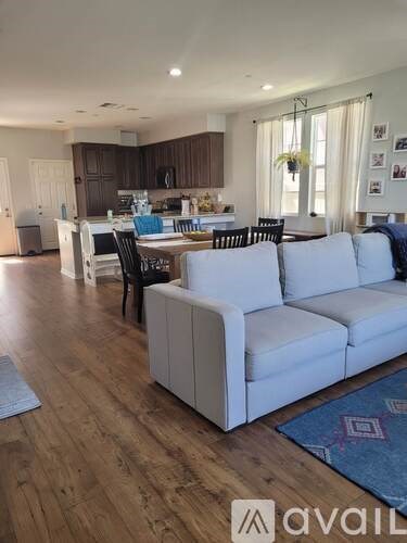 A living room with a white couch and a kitchen in the background.