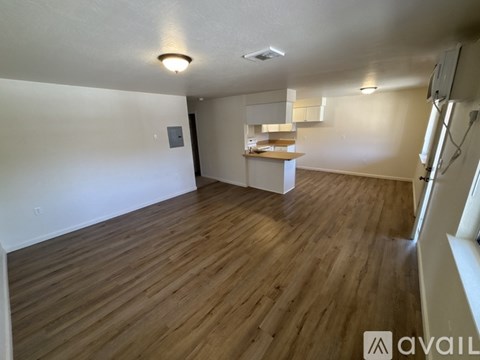 A room with wooden flooring and a kitchenette in the corner.