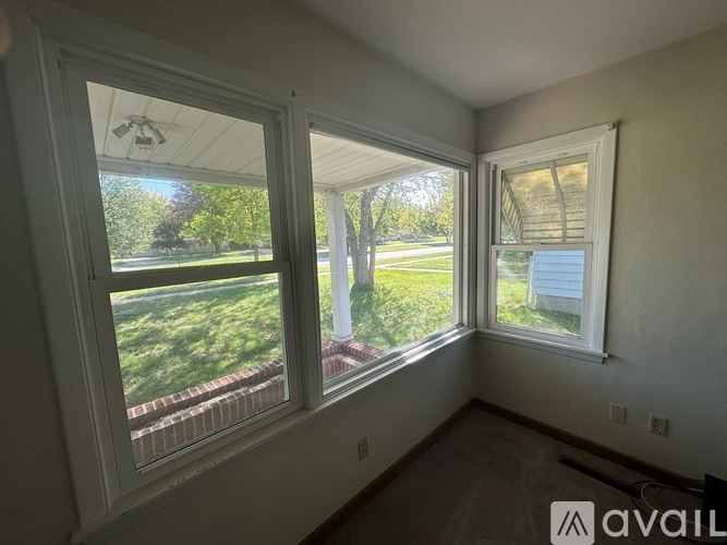 A room with two windows overlooking a green lawn.