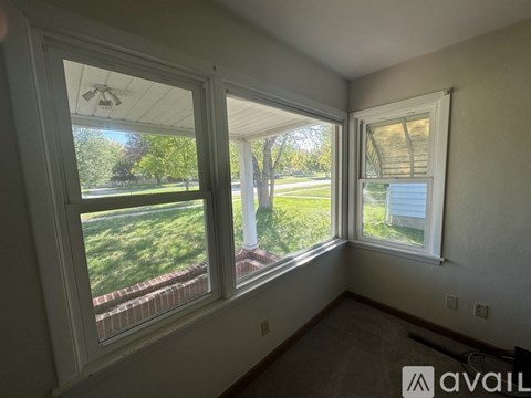 A room with two windows overlooking a green lawn.