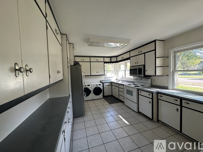 A kitchen with white cabinets and black countertops.