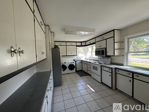 A kitchen with white cabinets and black countertops.