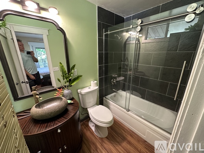A man is taking a picture in a bathroom with a large mirror.