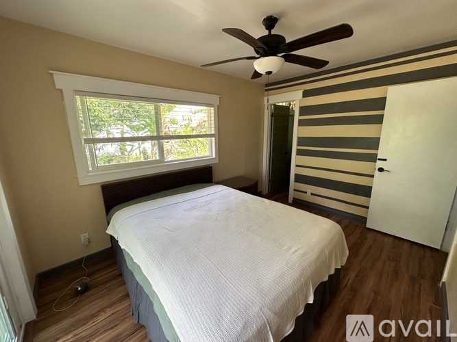 A bedroom with a bed, a window, and a ceiling fan.