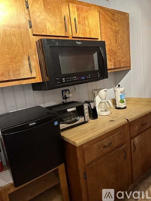 A black microwave is mounted above a black printer on a wooden counter.