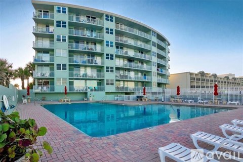 A large apartment complex with a pool in front.