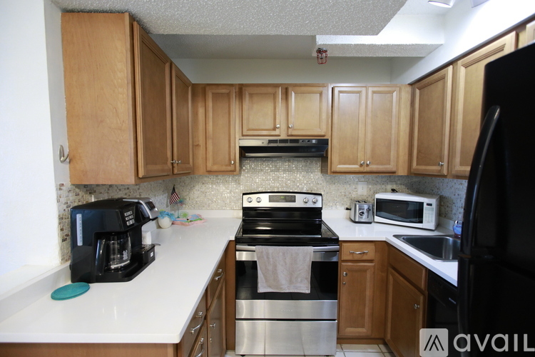 A kitchen with wooden cabinets and a black refrigerator.