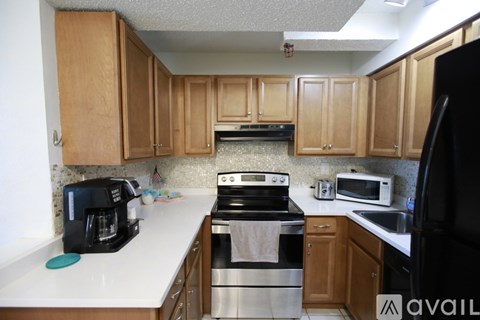 A kitchen with wooden cabinets and a black refrigerator.