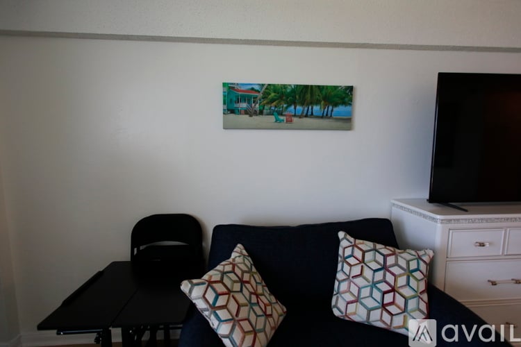A living room with a couch, chair, and a painting on the wall.
