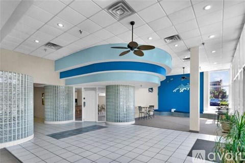 A spacious room with a fan and a blue wall.