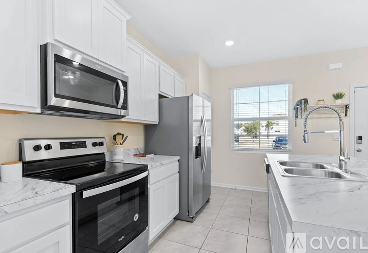 A kitchen with white cabinets and appliances, a window, and a sink.