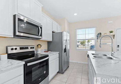 A kitchen with white cabinets and appliances, a window, and a sink.