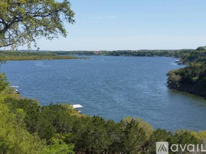 A large body of water surrounded by greenery and a boat in the distance.