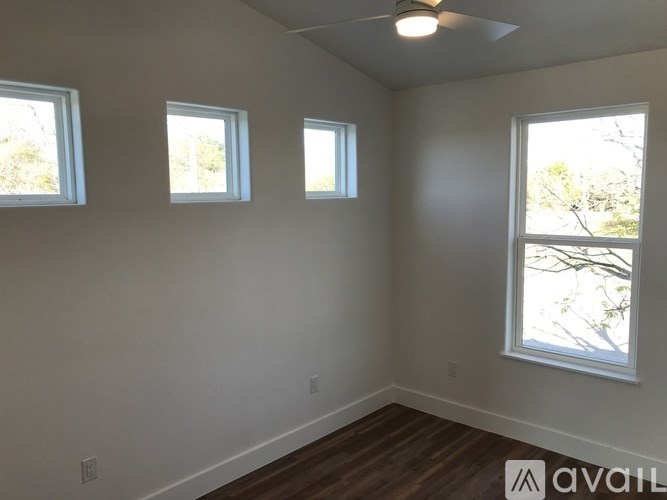 Three windows in a room with wooden floors and white walls.