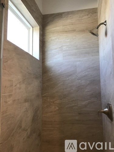 A bathroom with a tiled shower and a window.