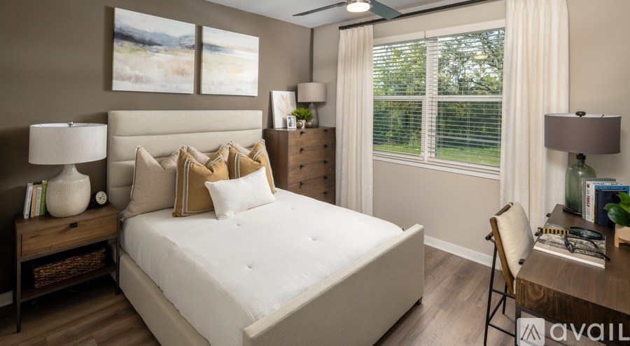 A well-lit bedroom with a large bed, a chair, and a desk.