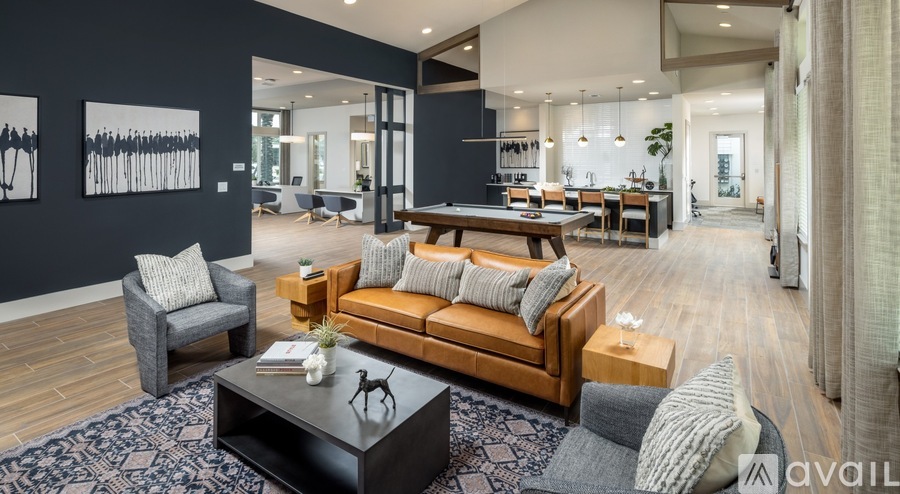 A modern living room with a dark blue rug and a wooden coffee table.