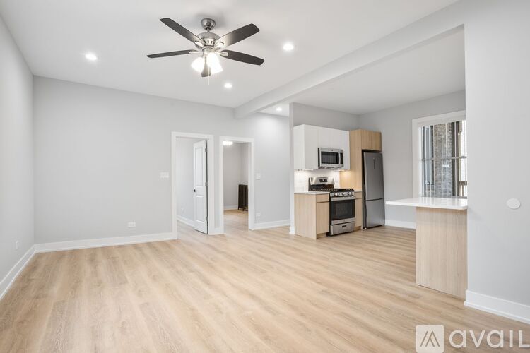 A spacious living room with a kitchenette and a ceiling fan.