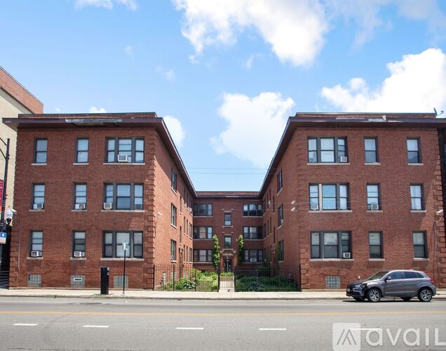 A red brick apartment building with a car parked in front.