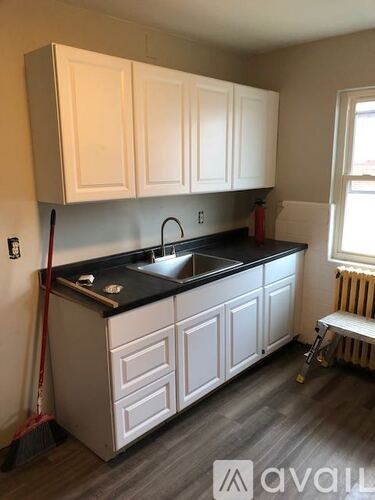 A kitchen with white cabinets and a black countertop.