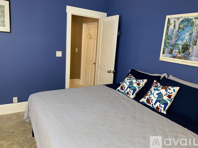 A bedroom with blue walls and a bed with two decorative pillows.