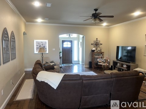 A living room with a brown couch and a ceiling fan.