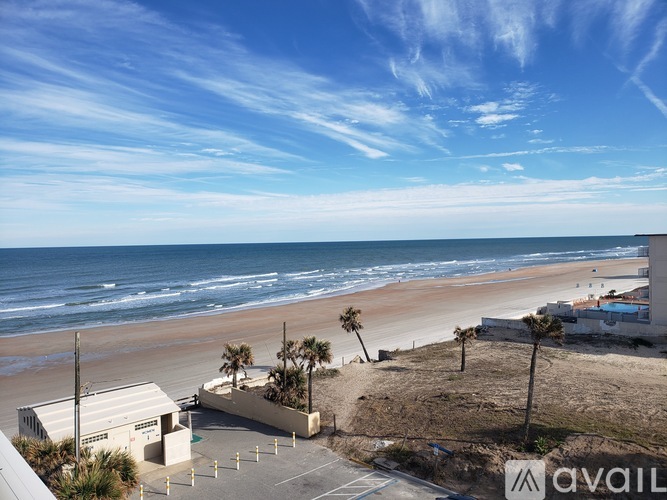 A beachfront view with a clear sky and a building with the text "AVAIL" on it.