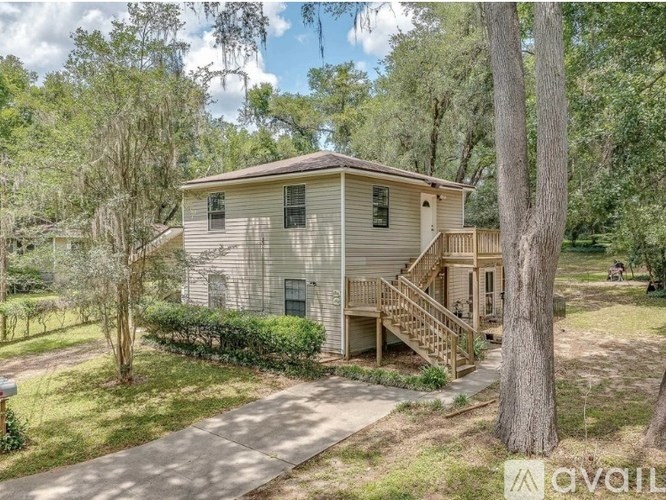 A house with a porch and a tree in front of it.